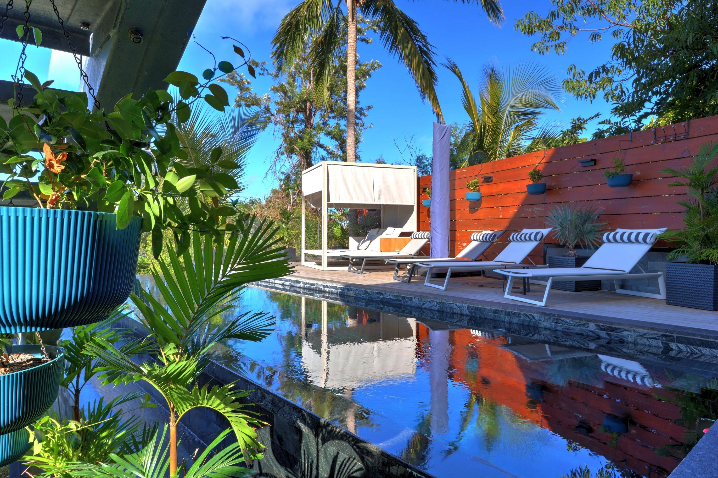 A pool area with lounge chairs, a small structure with a white canopy, and potted plants.