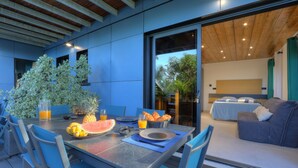 A modern outdoor dining area with a table set for two, featuring a fruit bowl, plates, and cutlery. - Studio Ananas - Vue mer et piscine partagée (Les Avirons)