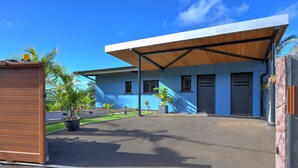 A modern building with a covered entrance, a paved driveway, and potted plants. - Studio Ananas - Vue mer et piscine partagée (Les Avirons)