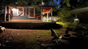 A covered outdoor area with a wooden deck, a hammock, and a table. - Maine Coast Mountain Retreat (Camden)