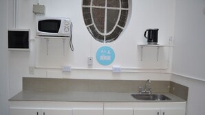 Una cocina con microondas, cafetera y lavabo.