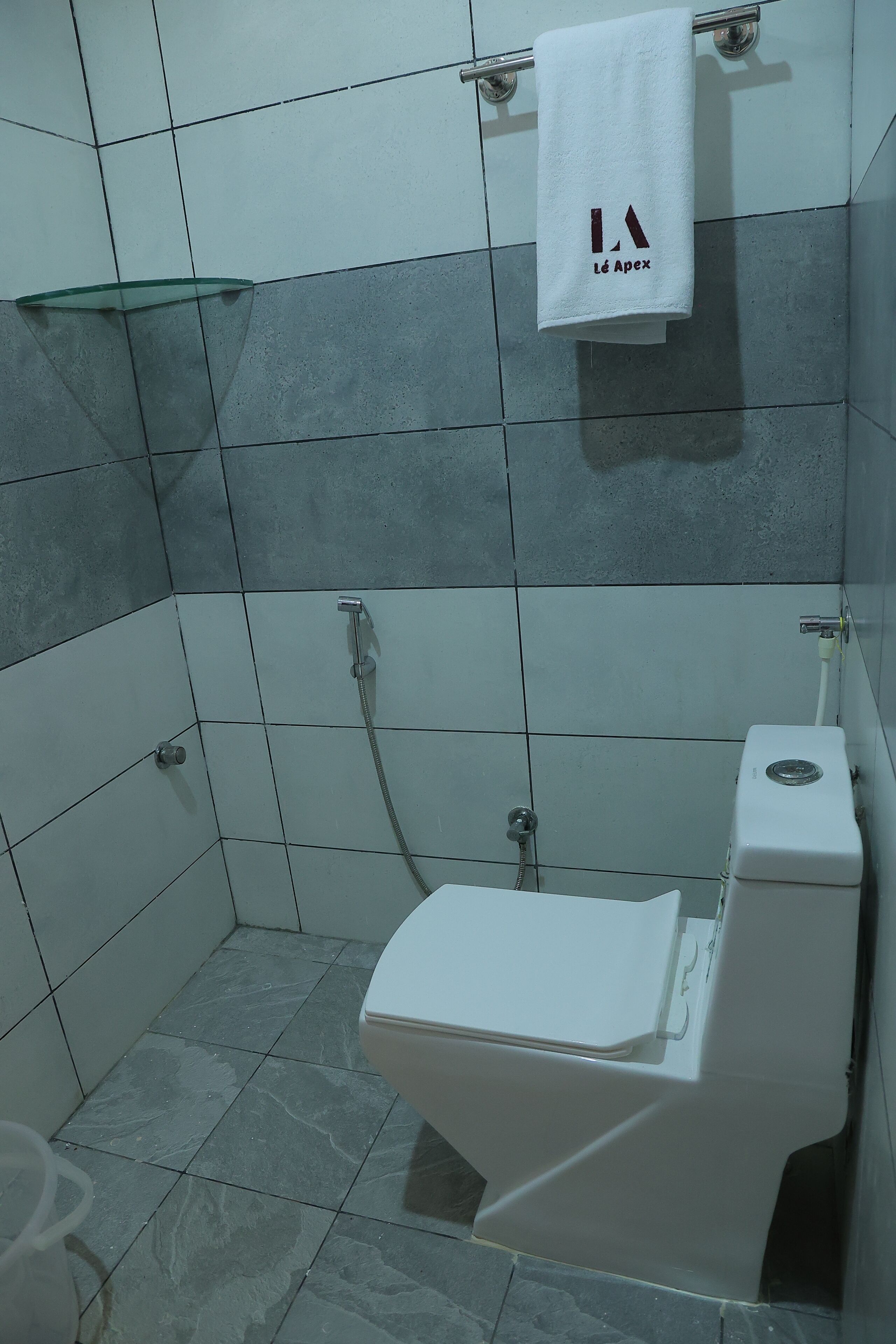 A bathroom with a toilet, a glass shower enclosure, and a towel hanging on a rack.