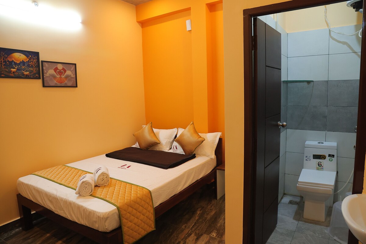 A hotel room with a bed, a bathroom with a toilet, and a shower.
