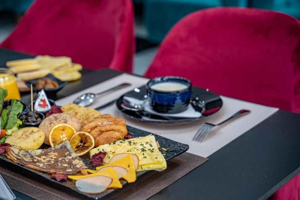 Un plateau de petit-déjeuner avec des œufs, des pommes de terre et une boisson, posé sur une table entourée de chaises rouges.