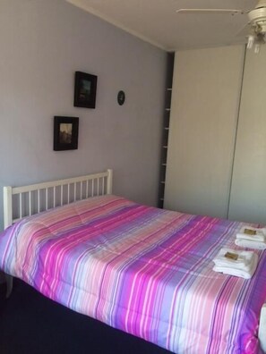 A bedroom with a bed, a white headboard, a wardrobe, and two framed pictures on the wall. - Pindo Guazu Hostel (Buenos Aires)