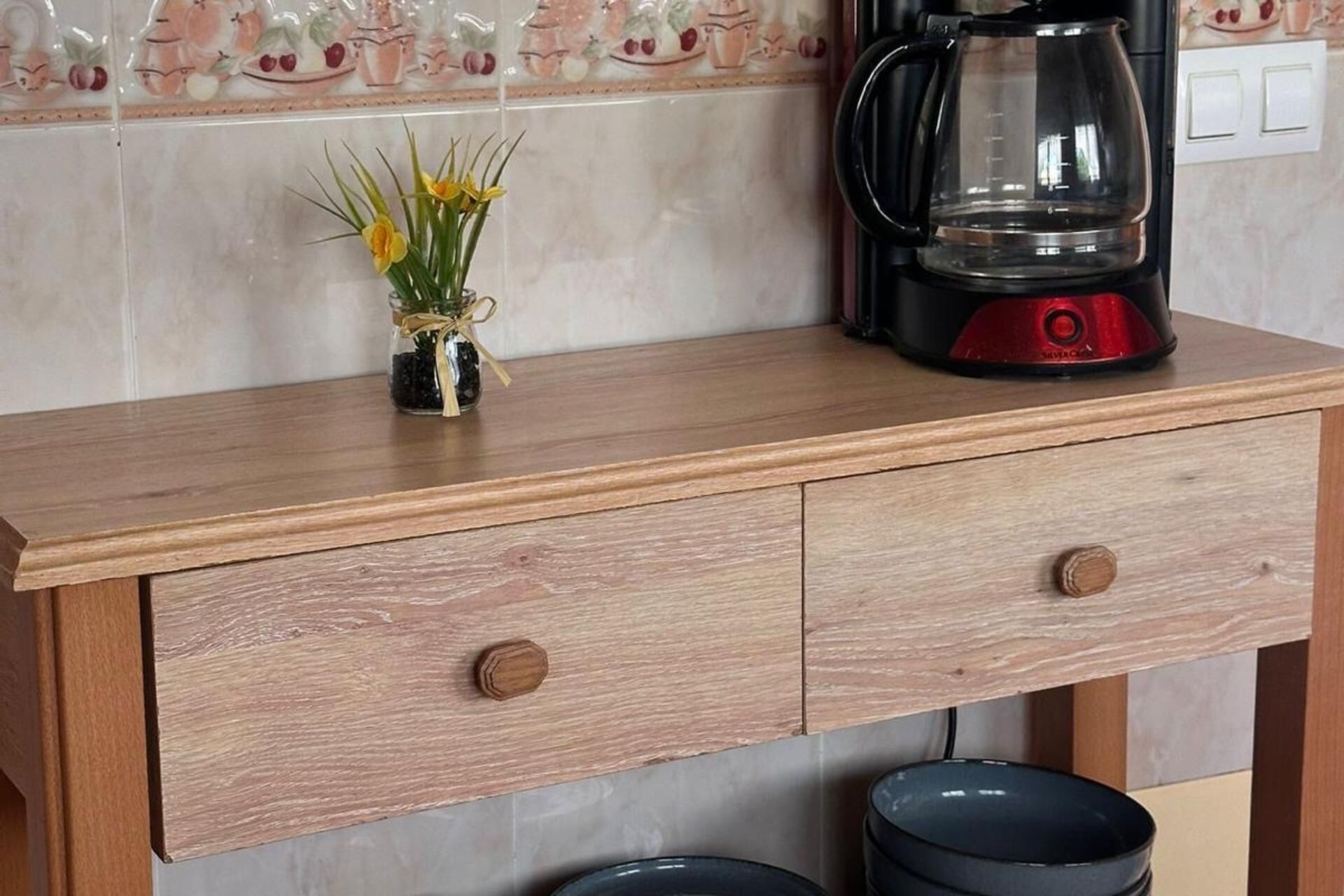 A kitchen counter with a coffee maker and a vase of flowers.