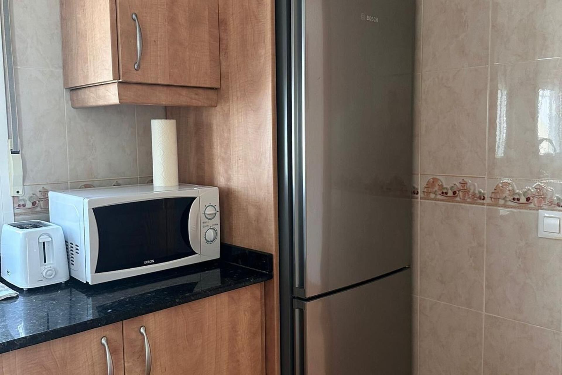 A kitchen with a white microwave, a toaster, and a stainless steel refrigerator.
