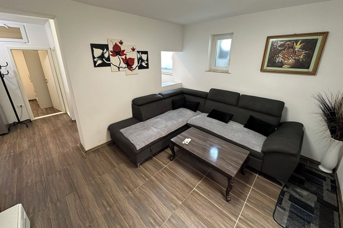 Un salon moderne avec un canapé d’angle, une table basse et des œuvres d’art accrochées aux murs.
