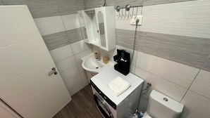 Une petite salle de bain comprenant un lavabo, des toilettes et un lave-linge.