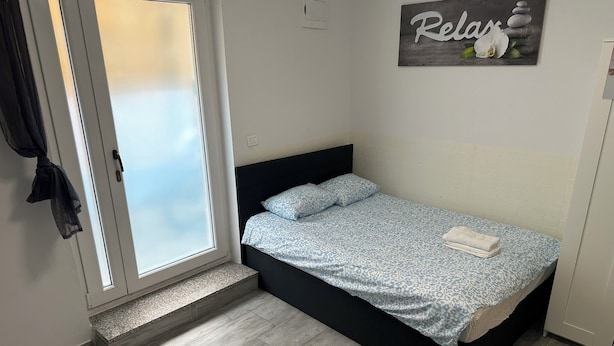 Une chambre avec un lit, une petite marche menant à une porte et un panneau fixé au mur.