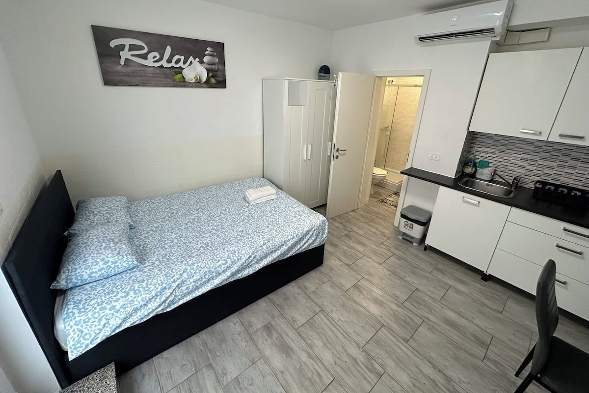 Une petite chambre propre, équipée d’un lit, d’une kitchenette et d’une salle de bain.