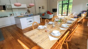 A spacious dining area with a long wooden table set for a meal, surrounded by wooden chairs. - The Old Creamery (Llandeilo)