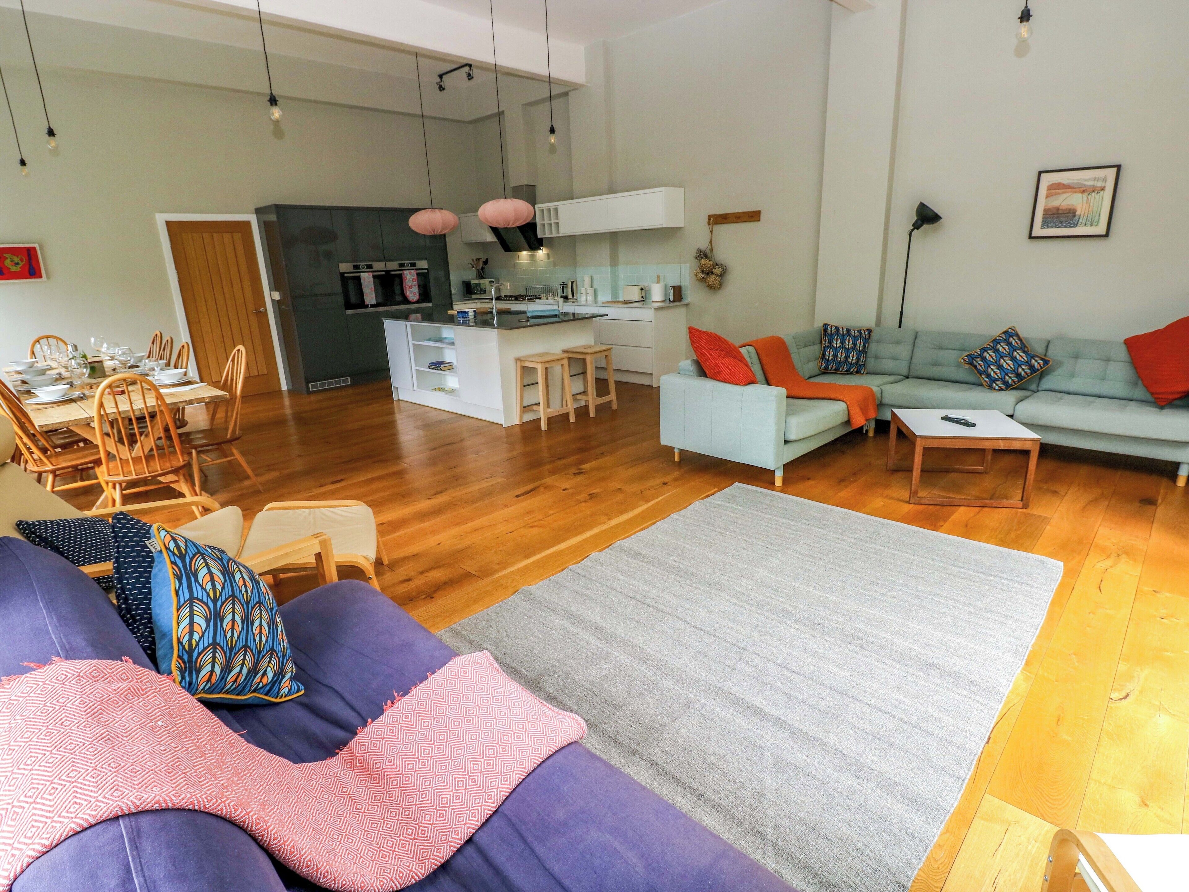 Un salon moderne avec un canapé, un coin repas et une cuisine en arrière-plan.