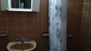 Un baño con lavamanos, espejo y cortina de ducha.