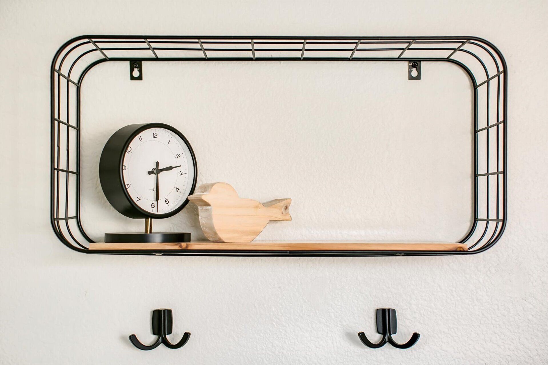 A wall-mounted shelf with a clock and a wooden sculpture.