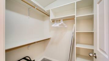 A walk-in closet with open shelving, a radiator, and a black chair.