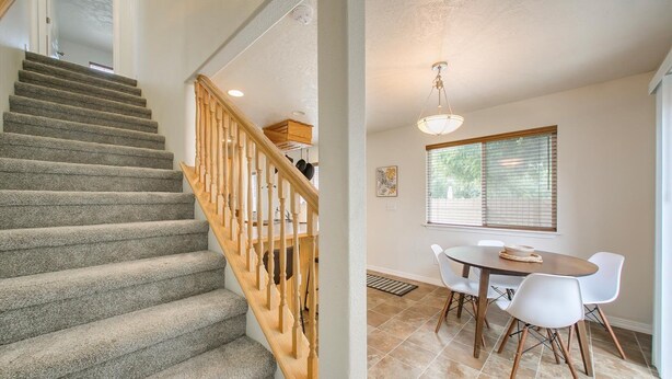 Eine Treppe mit Teppichstufen und Holzgeländern führt zu einem Essbereich mit Tisch und Stühlen.