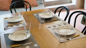 A dining table set with plates, cutlery, and glasses, with a striped couch and chairs in the background.
