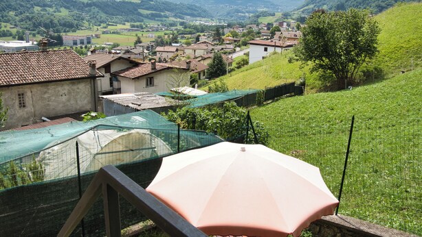 A rural village with traditional houses, a green field, and mountains in the background.