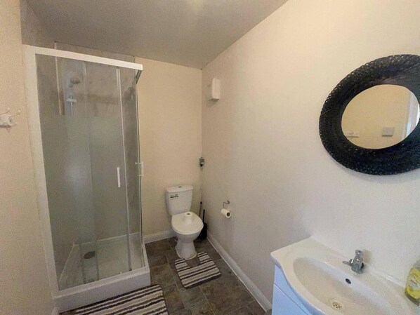 A bathroom with a glass-enclosed shower, a toilet, and a sink with a mirror. - Bristol Bliss Apartment - Patchway Retreat (Bristol)