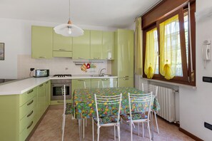 A kitchen with green cabinets, a stove, and a dining table with chairs.