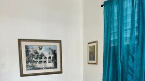 Una sala de estar con un sofá estampado, un cuadro en la pared y una cortina color turquesa.