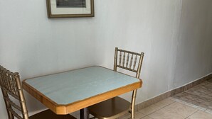 Una mesa de comedor con dos sillas, un cuadro en la pared y piso de baldosas.