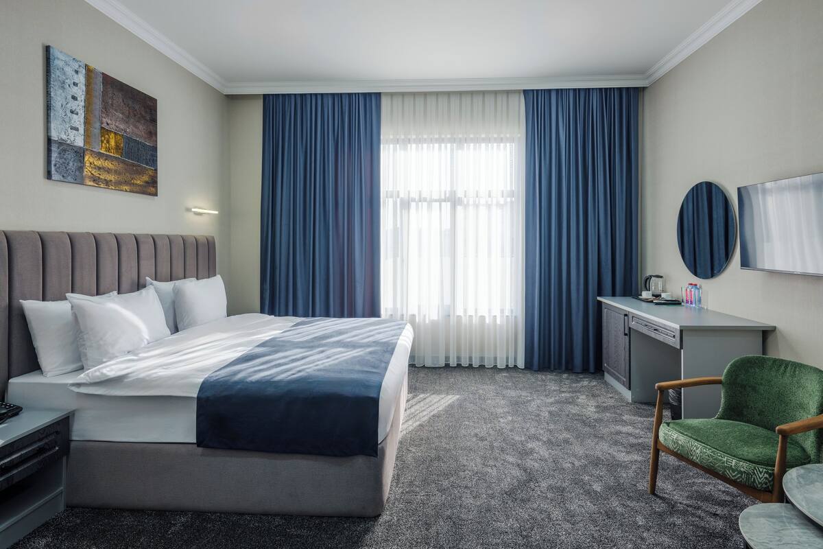 A hotel room with a bed, a desk, a chair, and a TV.
