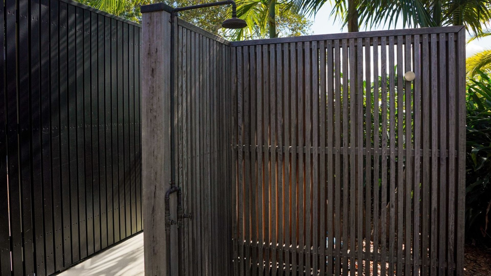 A metal gate with a vertical bar design, a handle, and a small circular object on top.