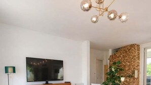 Una sala de estar moderna con un televisor de pantalla plana grande, sofás azules, una mesa de centro de madera y un elemento decorativo único en la pared.