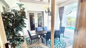 Une terrasse avec une table et des chaises, un pot de fleurs et une vue sur une piscine.