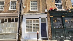 A multi-story brick building with a ground-floor shop and a dark green door. - Stunning 4 Bed Town House w/ Roof Terrace in Farringdon / St Paul's Cathedral (London)