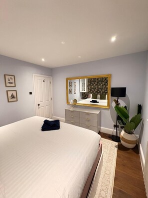 A bedroom with a large bed, a dresser, a mirror, a plant, and a lamp. - Stunning 4 Bed Town House w/ Roof Terrace in Farringdon / St Paul's Cathedral (London)
