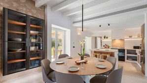 A modern kitchen with a dining area, featuring a round table, chairs, and a built-in shelving unit. - Villa 'Can Mas  Antigua' with Mountain View, Wi-Fi and Air Conditioning (Illes Balears)