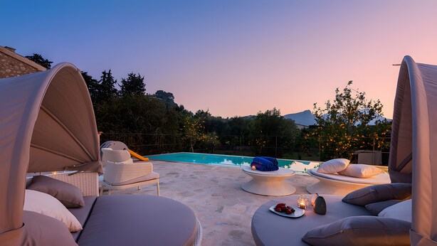 A poolside area with lounge chairs, a table with a blanket and a bottle, and a view of the pool. - Villa 'Can Mas  Antigua' with Mountain View, Wi-Fi and Air Conditioning (Illes Balears)