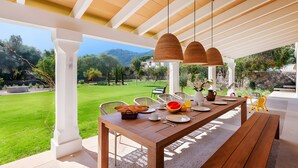 An outdoor dining area with a wooden table, chairs, and hanging pendant lights. - Villa 'Can Mas  Antigua' with Mountain View, Wi-Fi and Air Conditioning (Illes Balears)