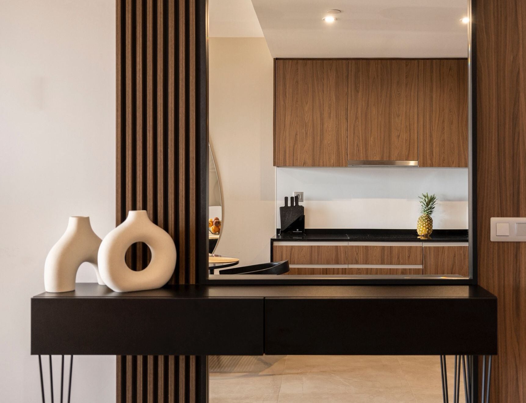 Una cocina moderna con armarios de madera, encimera negra y jarrones decorativos.