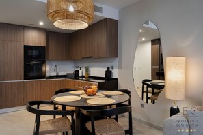 A modern kitchen with wooden cabinets, a black stove, and a dining area with a round table and chairs. - Sunset Cliffs Sea View (Benidorm)