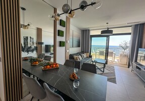 A modern living room with a dining area, a sofa, and a view of the outdoors.