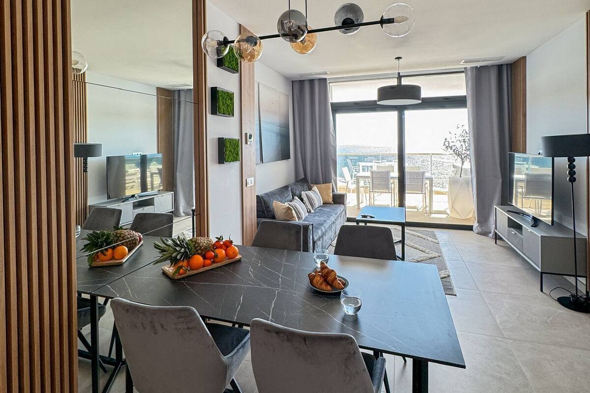 A modern living room with a dining area, large windows, and a view of the outdoors.