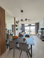 Una sala de estar moderna con comedor, ventanas amplias y vistas al exterior.