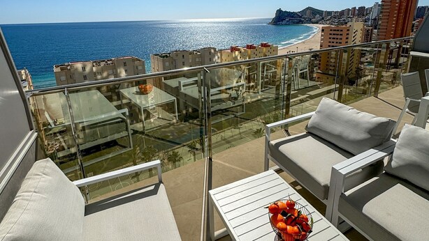 A balcony with a view of the sea, white furniture, and a table with a fruit basket. - Sunset Cliffs Sea View (Benidorm)