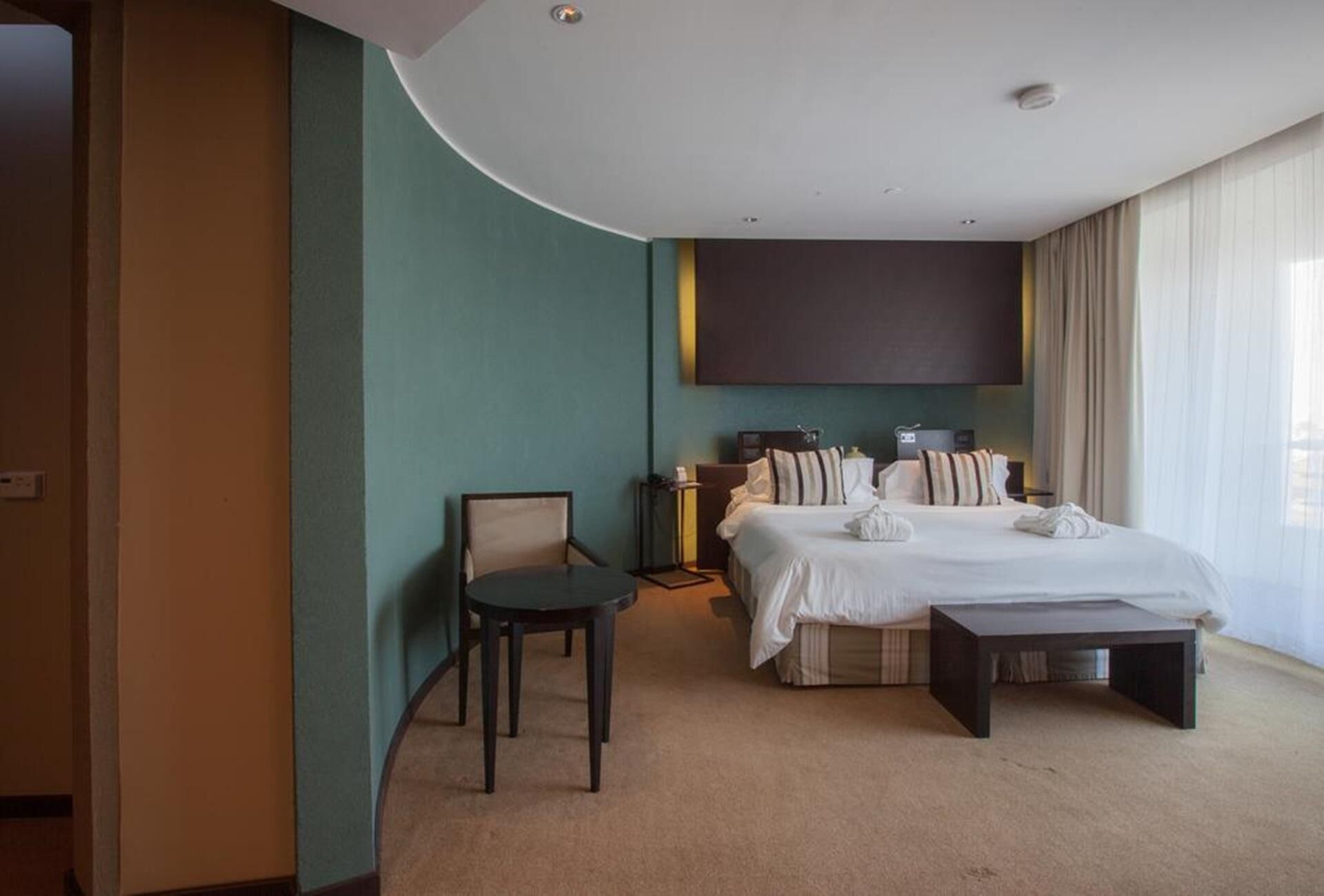 Habitación de hotel con una cama grande, un escritorio, una silla y un televisor montado en la pared.