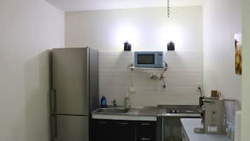 Cocina compacta con refrigerador, microondas, fregadero y cafetera.
