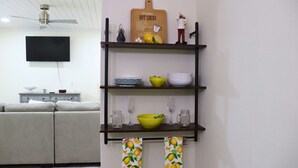 A modern living room with a grey sofa, a flat-screen TV, a wooden shelf with kitchenware, and a ceiling fan. - Harbor Side Retreat (Port Charlotte)