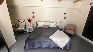 A bedroom with a large bed, two bedside tables, a chair, and a wardrobe.