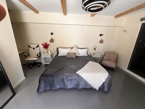 Une chambre à coucher avec un grand lit, deux tables de chevet, une chaise et une armoire.