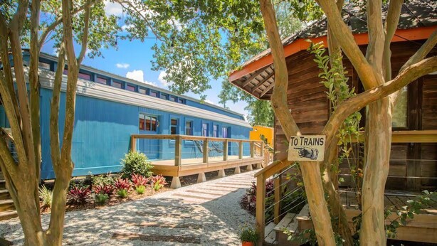 Un tren azul con cubierta de madera, un letrero que dice 'TO TRAINS' y una estructura de madera con techo.