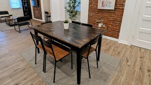 Un coin repas avec une table et des chaises en bois, une plante en pot et un mur en briques.