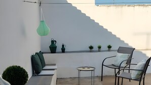 Une terrasse sur le toit, aménagée avec un espace salon, une table et des plantes en pot.